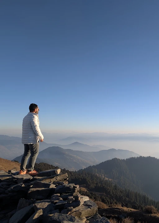 Hardeep standing on a mountaintop overlooking a valley